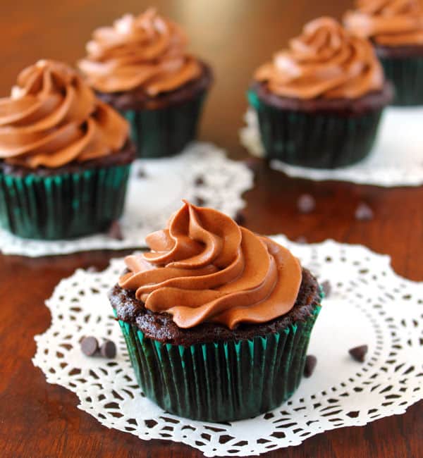 Chocolate Zucchini Cupcakes with chocolate Cream Cheese Frosting sitting on white paper doilies