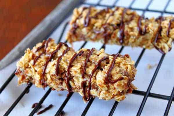 two Chewy Peanut Butter Granola Bars on a cooling rack and drizzled with chocolate