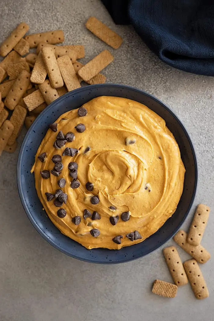 Overhead view of pumpkin dip garnished with extra chocolate chips and graham cracker sticks off to the side. 