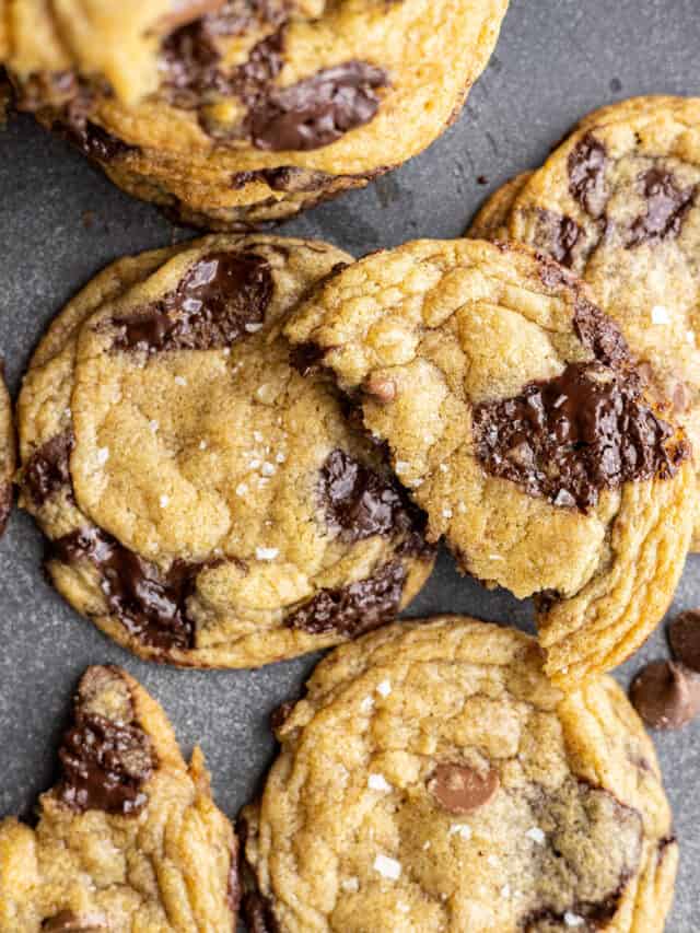 Overhead view of chocolate chip cookies. One broken in half sitting on top of the cookies.