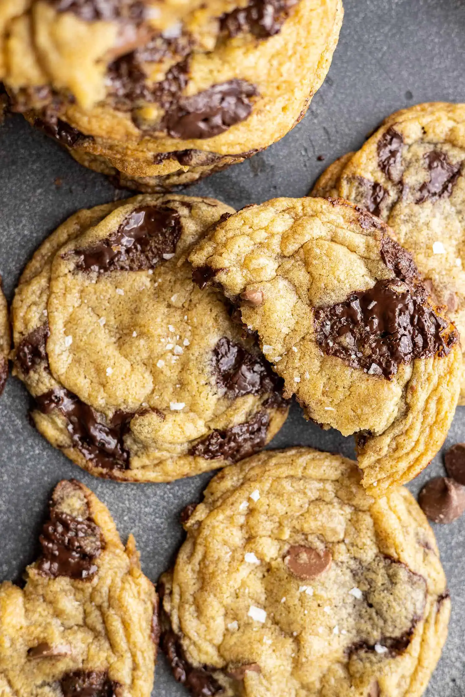 Overhead view of chocolate chip cookies. One broken in half sitting on top of the cookies.