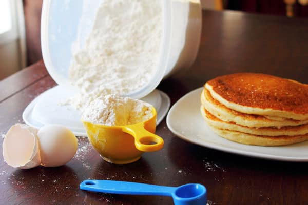 simple homemade pancake pix in a bowl beside a plate of cooked pancakes