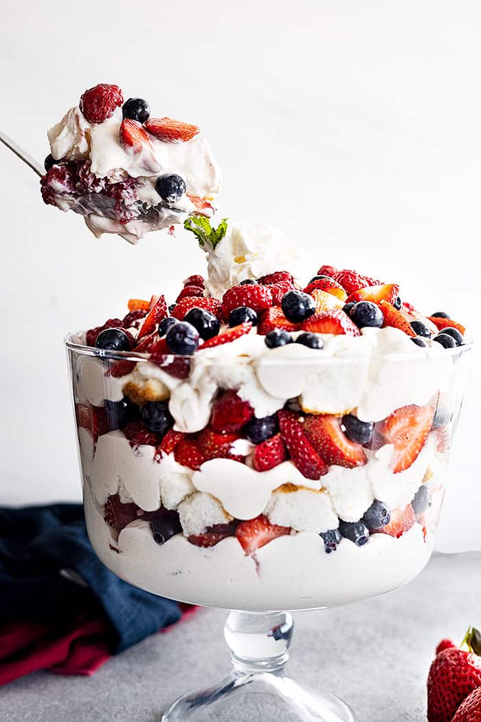 A large spoon dishing up a portion of berry coconut trifle.