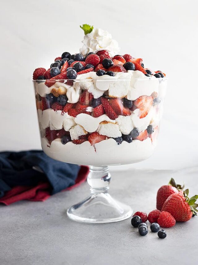 A trifle bowl filled with angel food cake, coconut cheesecake filling, strawberries, blueberries, and raspberries. All in pretty layers.