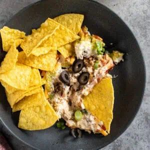 Overhead picture of taco dip on a plate with chips surrounding it.
