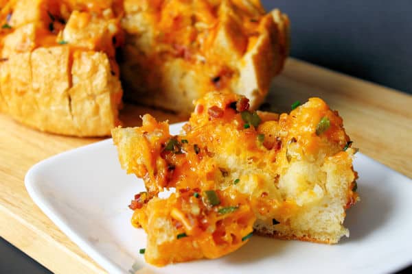 jalepeno cheese bread with bacon pulled apart with one serving on a small white plate in the foreground