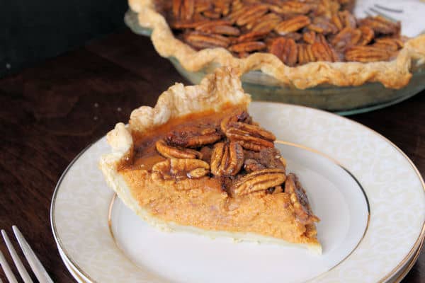 a slice of easy Pumpkin Pie with Candied Pecans on a plate with the whole pie in the background