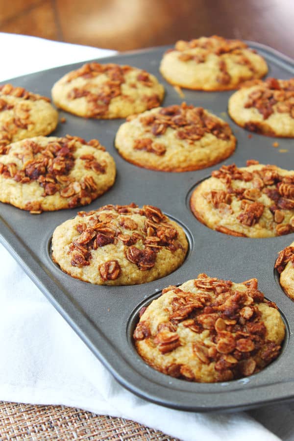 toasted oatmeal banana muffins in a muffin tin and covered in pecans
