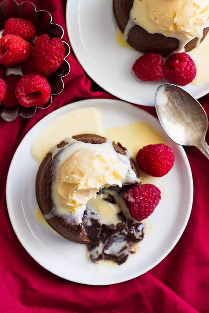 Chocolate Molten Lava Cake topped with ice cream and the chocolate center is flowing onto the plate. 