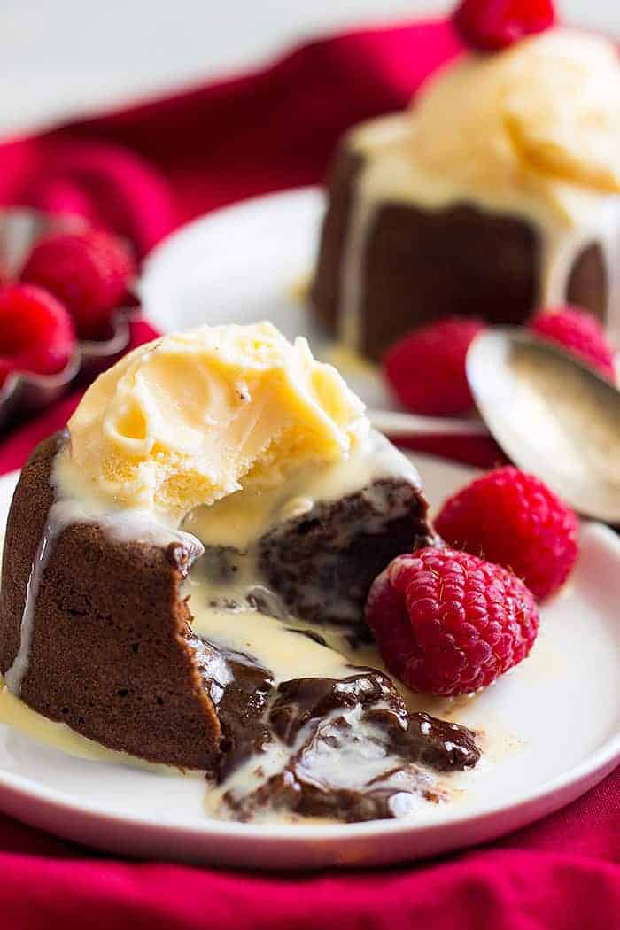 Chocolate Molten Lava Cake topped with soft slightly melting ice cream. The warm chocolate center is flowing onto the plate. 