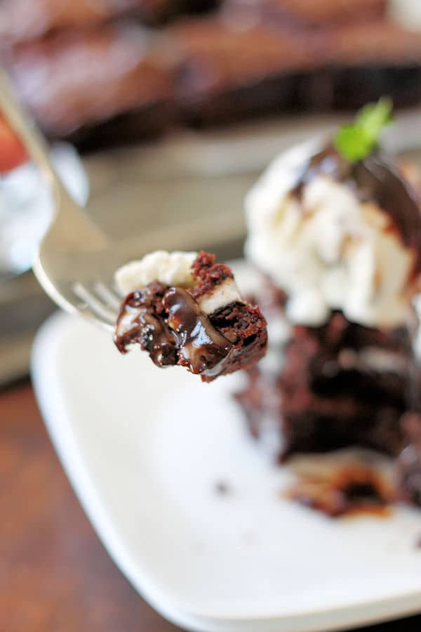 a forkful of a peppermint brownie paired with vanilla ice cream and drizzled with hot fudge sauce