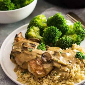 White plate with broccoli, rice, chicken, and a mushroom cream sauce drizzled on top