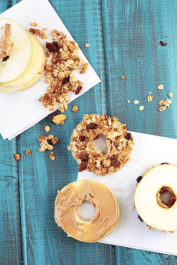 various donut shaped apple slices with peanut butter and granola on top
