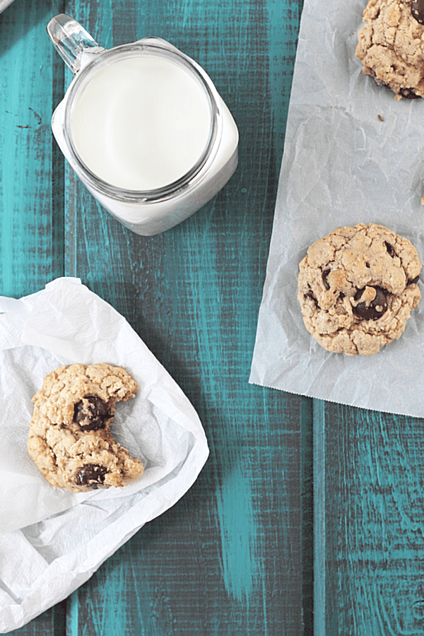 Chocolate Chip Oatmeal Cookies scattered about with a mason jar full of milk on the side