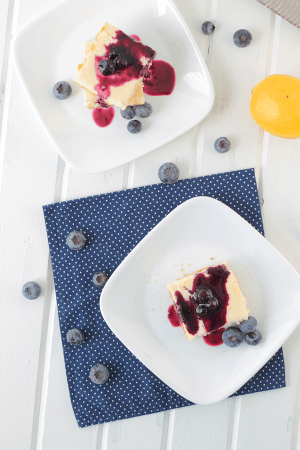 Lemon Cheesecake Bars on white plates with blueberry topping