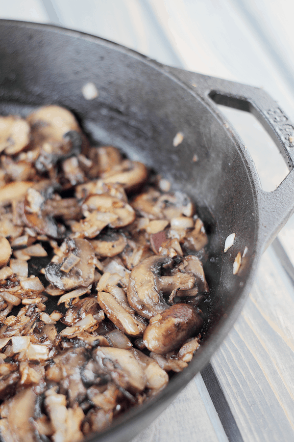 mushrooms and onions sauteed in a cast iron pan for the strata 
