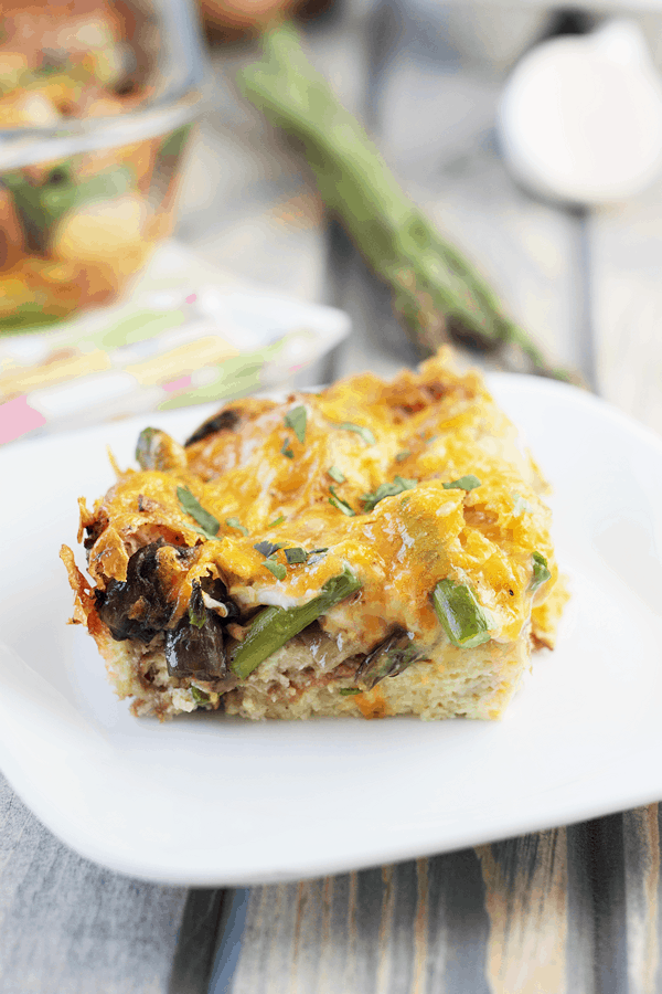 a slice of this mushroom and asparagus strata recipe on a white plate