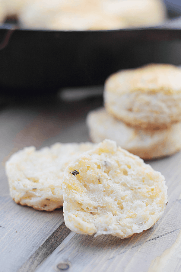closeup shot of rosemary cheddar biscuits halved with two unfocused in the background