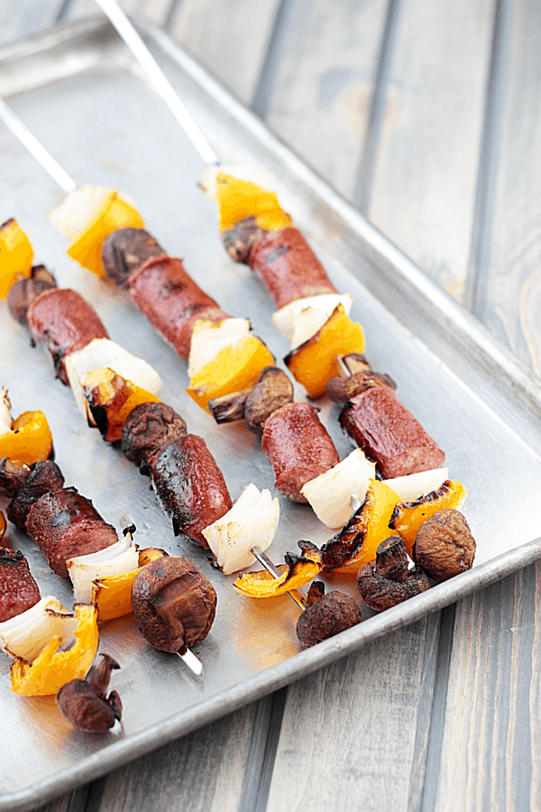 sausage and veggie skewers on a siilver baking tray