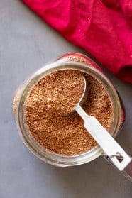 Top down of taco seasoning in a jar with a measuring spoon in it.