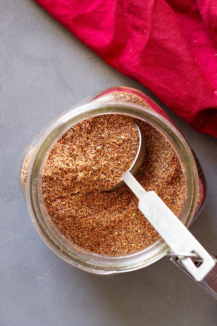 Top down of taco seasoning in a jar with a measuring spoon in it. 