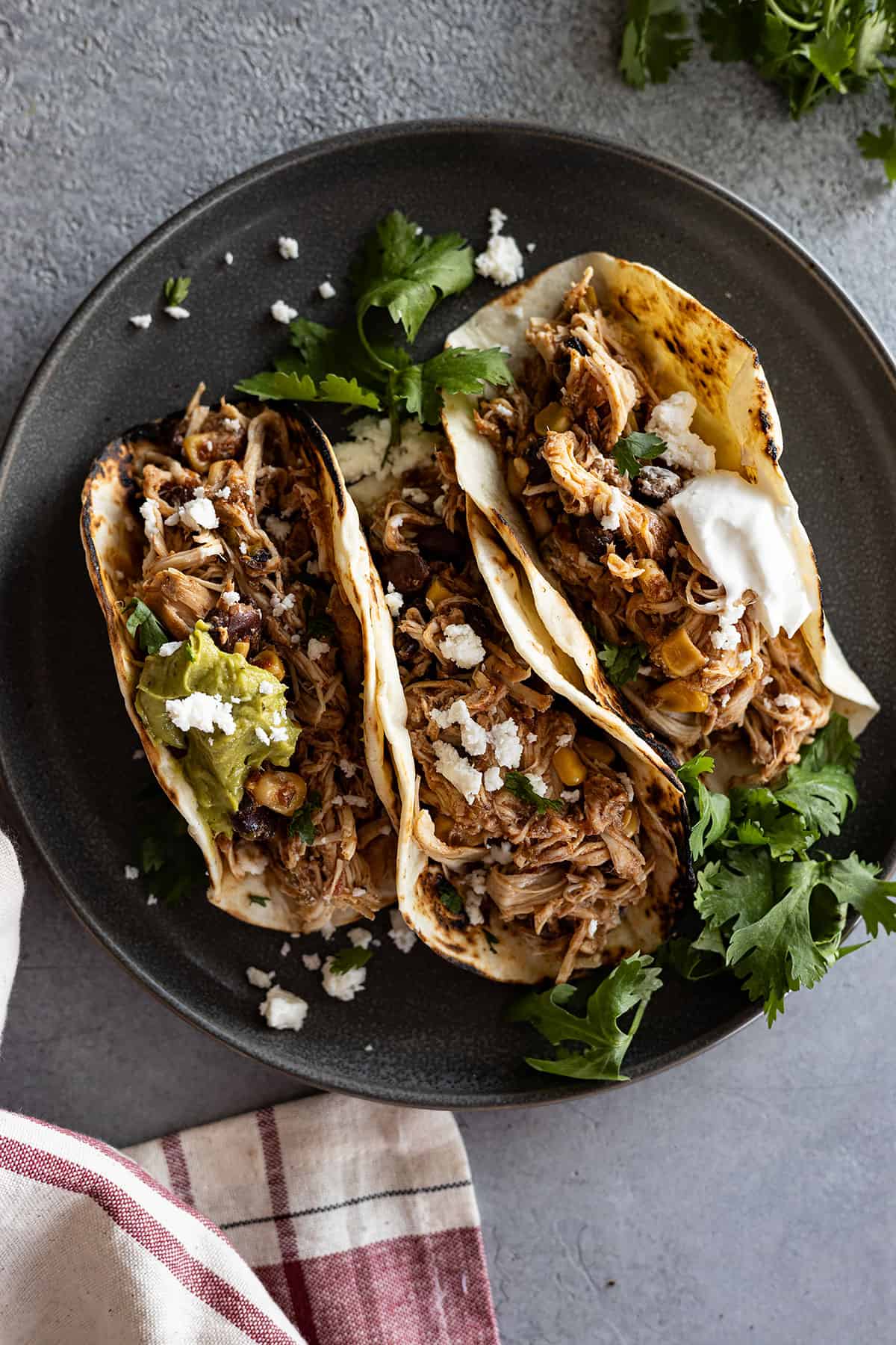 Overhead picture of southwest chicken stuffed into toasted corn tortillas. Topped with sour cream, cheese, and cilantro.