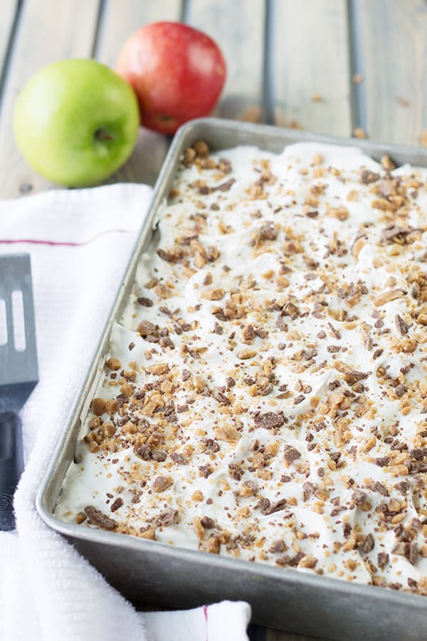 a silver baking tray full of caramel apple cake topped with toffee bits