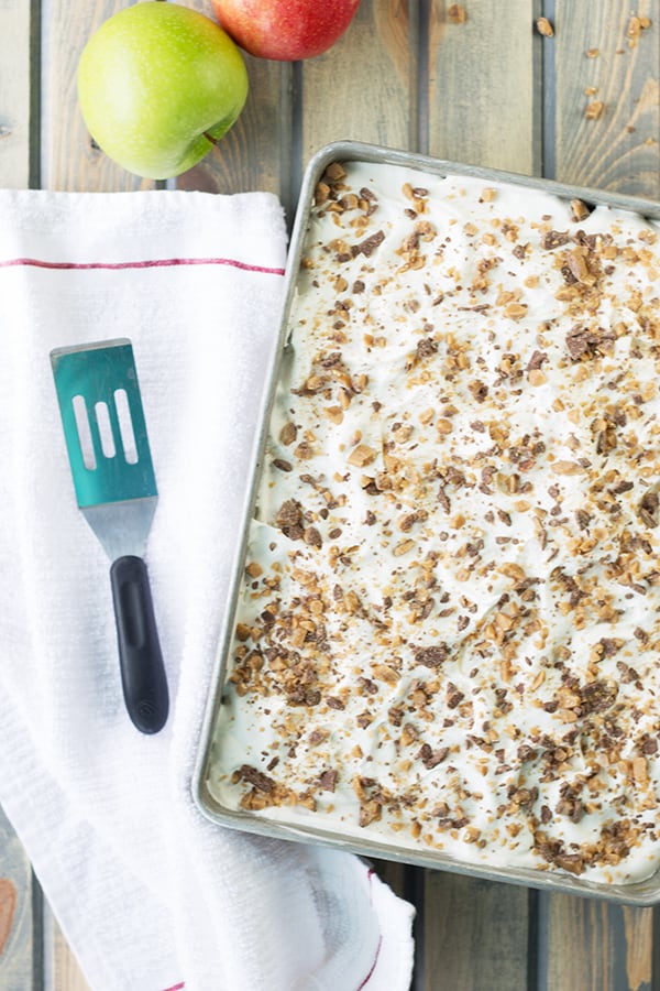 an overhead shot of the baking tray full of caramel apple cake with a serving spatula beside it on a white tea towel