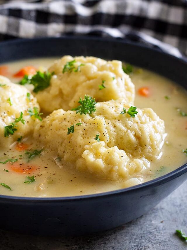 Close up of a bowl of creamy turkey and dumpling soup. Garnished with a little chopped parsley and black pepper.