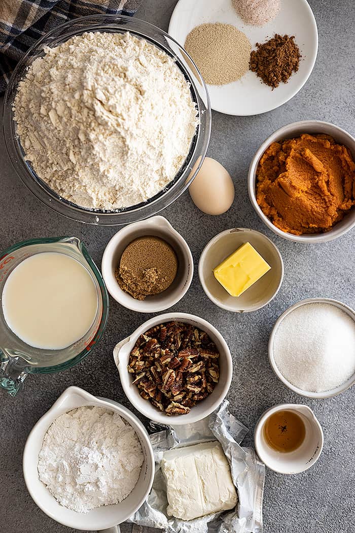 Overhead view of all ingredients needed to make pumpkin cinnamon rolls with cream cheese frosting.