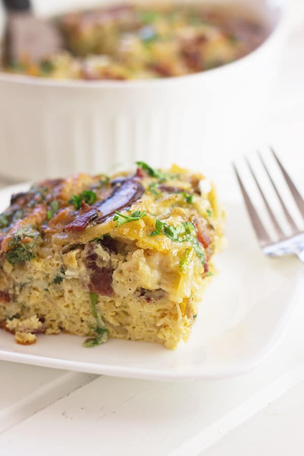 a close up photo of a slice of bacon, mushroom and spinach breakfast casserole