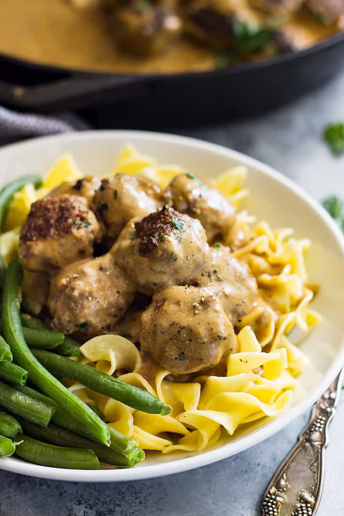 Swedish meatballs piled high on top of egg noodles with a side of green beans. 