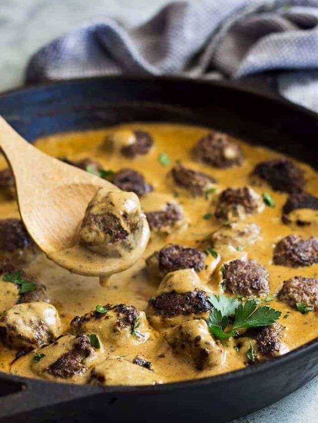 Pan of swedish meatballs with a spoon lifting one out.