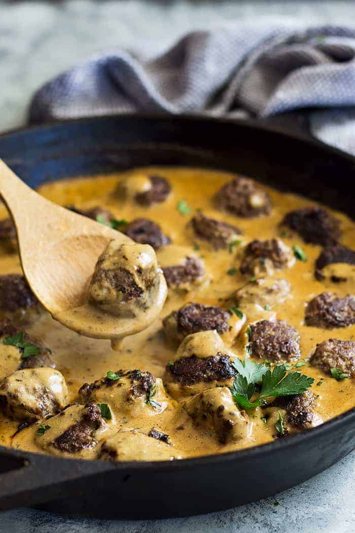 Pan of swedish meatballs with a spoon lifting one out. 