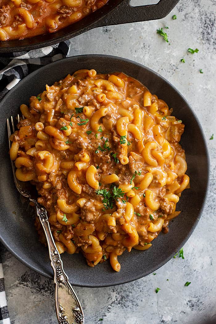 A plate piled high with hamburger helper and garnished with parlsey. 