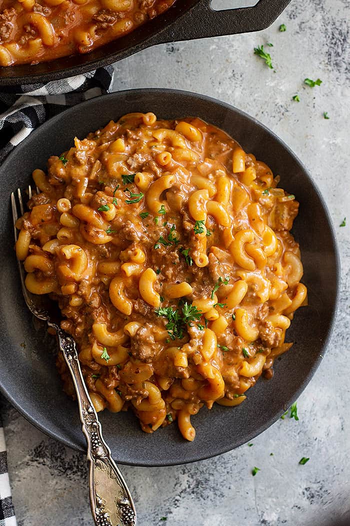 A plate piled high with hamburger helper and garnished with parlsey.