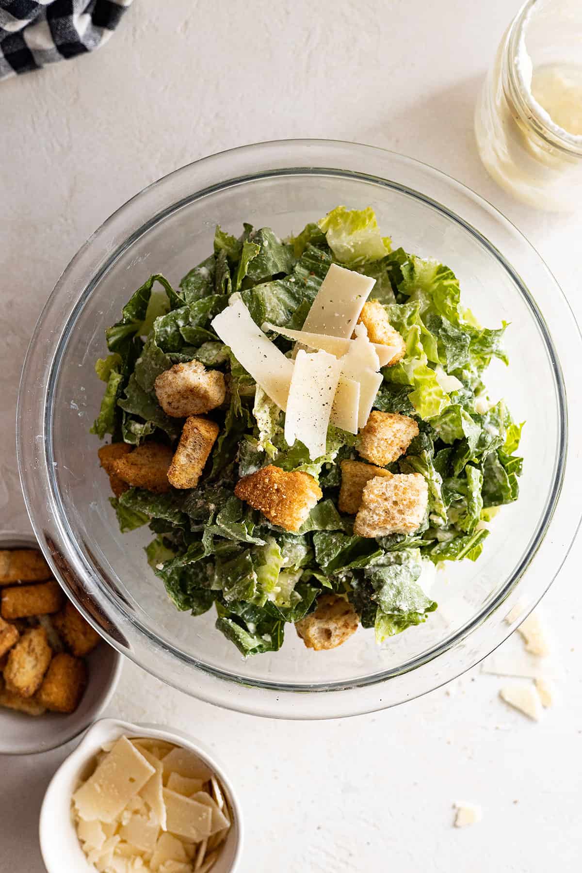 Overhead view of caesar salad in a bowl dressed with dressing, parmesan, and croutons. 