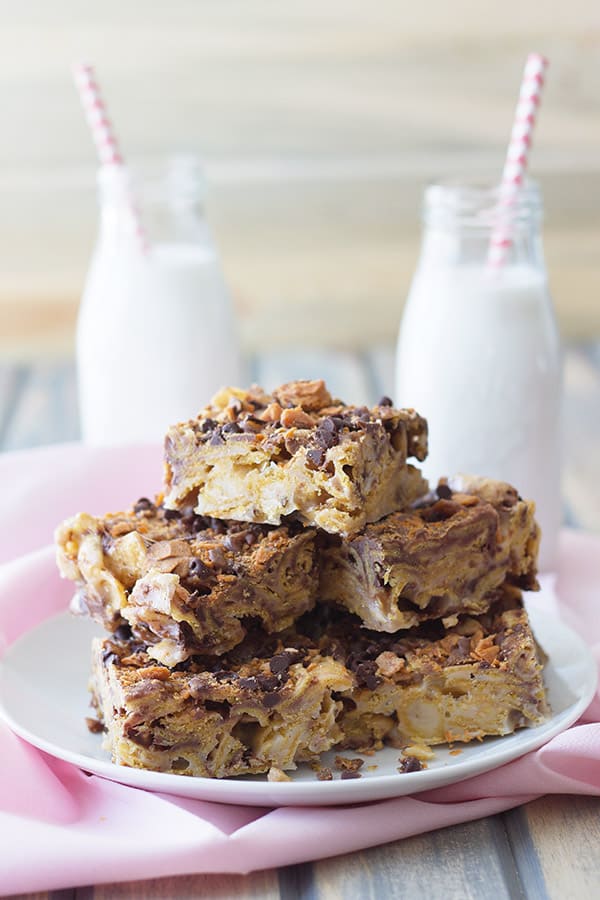 a stack of frito bars on a white plate in front of two glasses of milk