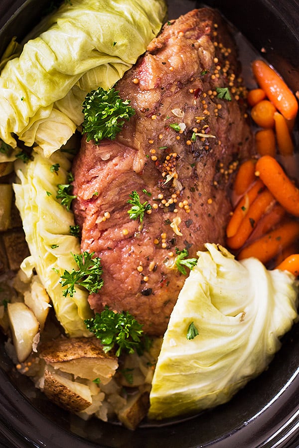 Top down of corned beef, cabbage, potatoes, and carrots in a slow cooker. 