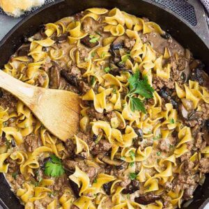 A top down view of one pot hamburger stroganoff in a pan with a spoon.