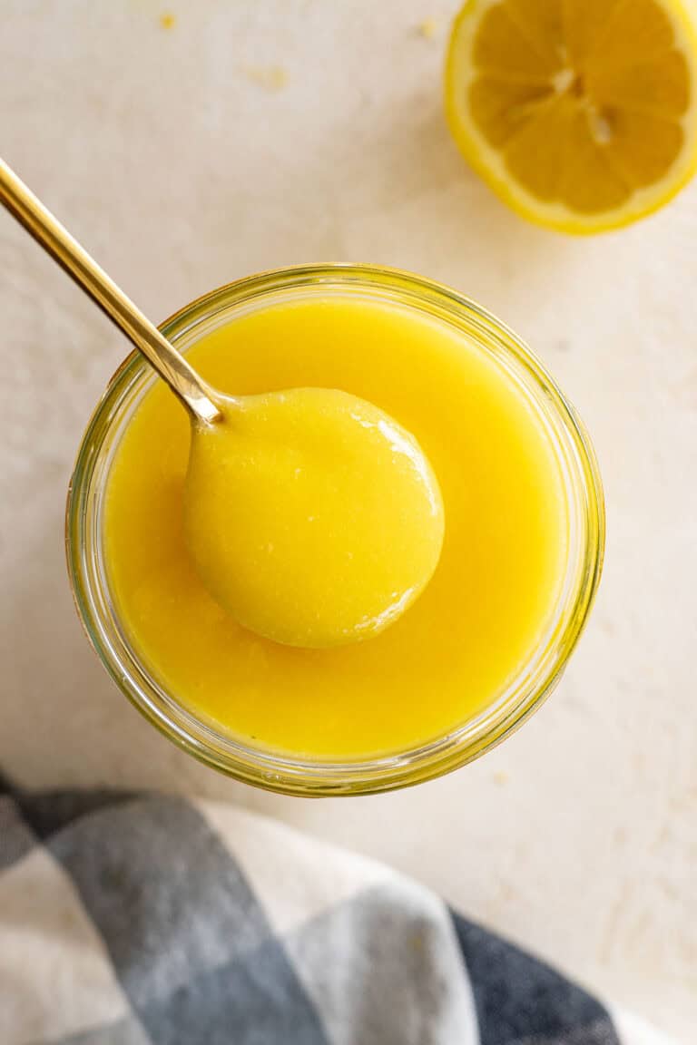Overhead view of lemon curd in a jar with a spoon in it.