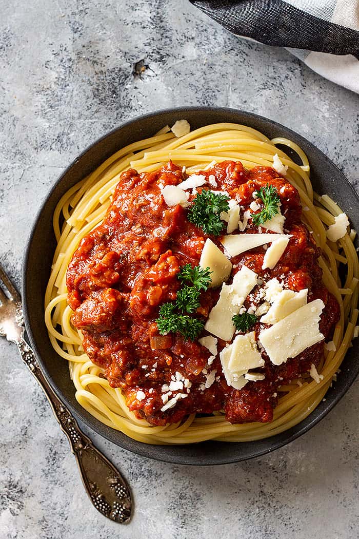 Top down view of spaghetti sauce over noodles and topped with cheese.