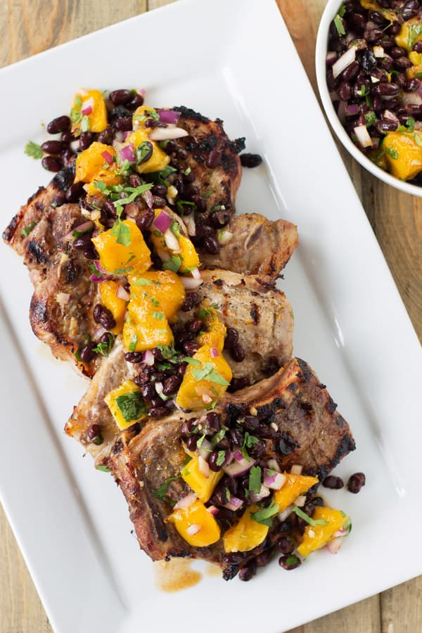 photo from above of grilled citrus pork chops topped with mango black bean salsa