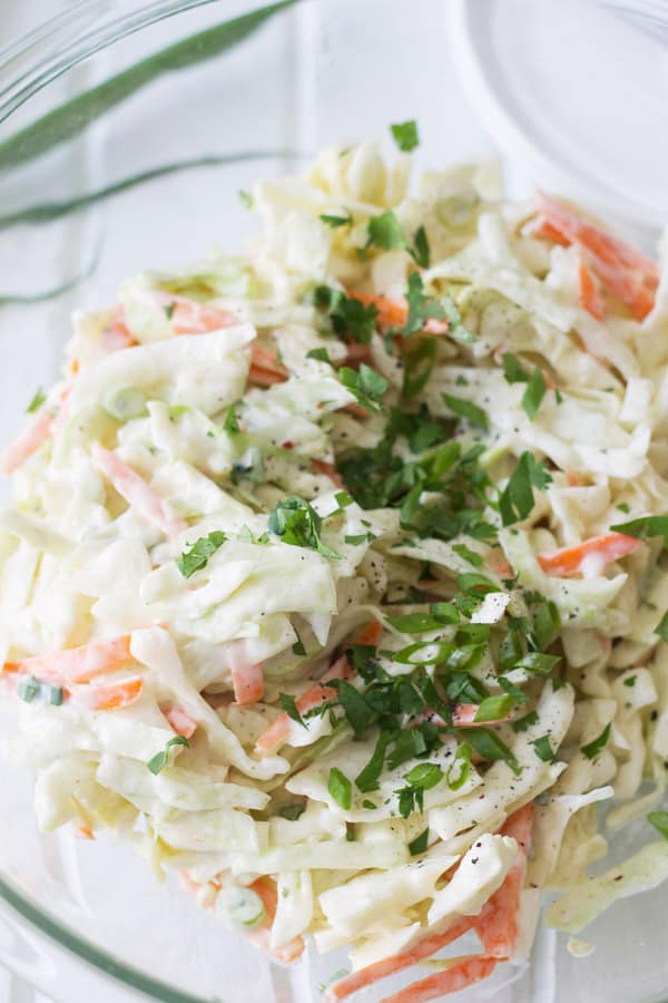 Closeup of creamy coleslaw in glass mixing bowl.