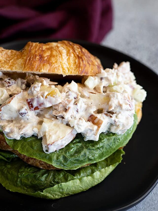 Apple tuna salad piled on a buttery croissant with a leaf of lettuce..