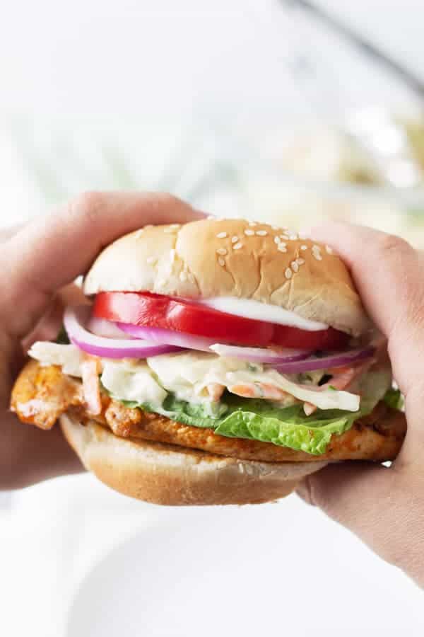two hands holding buffalo grilled chicken sandwich