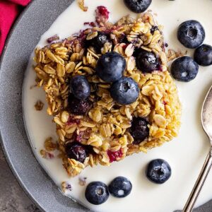 Baked oatmeal in a bowl topped with fresh blueberries and a splash of milk.