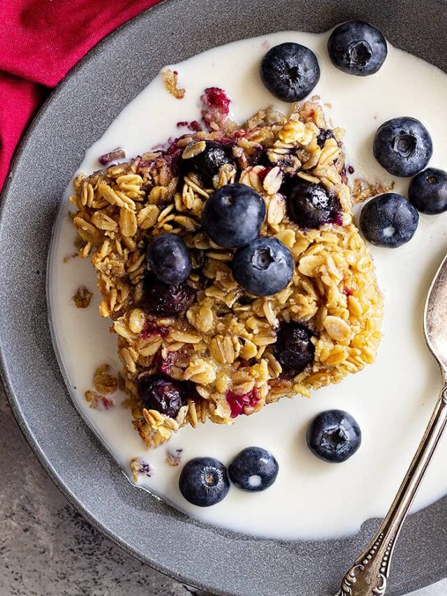 Baked oatmeal in a bowl topped with fresh blueberries and a splash of milk.