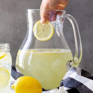 Dropping a cut lemon into the lemonade.