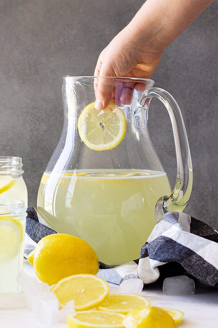 Dropping a cut lemon into the lemonade.
